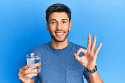 a man holding a glass of water and a peace sign