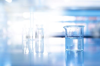Glass beaker in blue science chemistry laboratory background