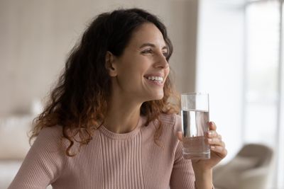 A woman with clear, healthy skin holding a glass of water