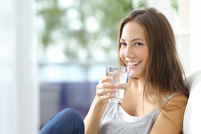 Youthful woman with clear skin holding a glass of water