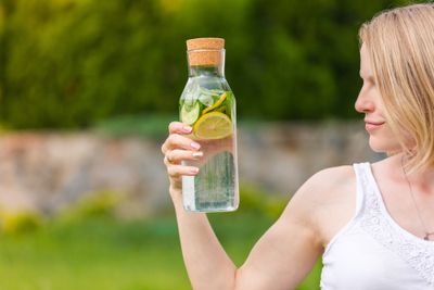 A woman holding a bottle of fruit-infused water.