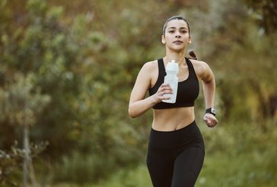 A woman running and holding a bottle of water.