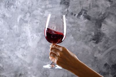Close-up of a person's hand swirling red wine in a wine glass