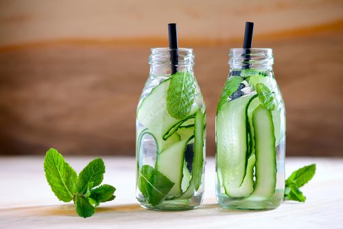 Two mason jars filled with water that contains cucumbers and mint leaves: Natural Hydration Drinks
