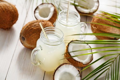A table with coconuts and two mason jars of coconut water - Natural Hydration Drinks