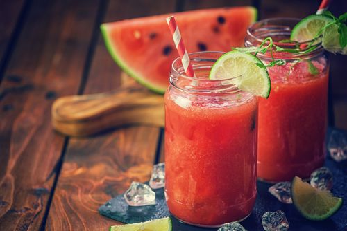 Two glasses of watermelon lime juice in mason jars, on a wooden table - Natural Hydration Drinks