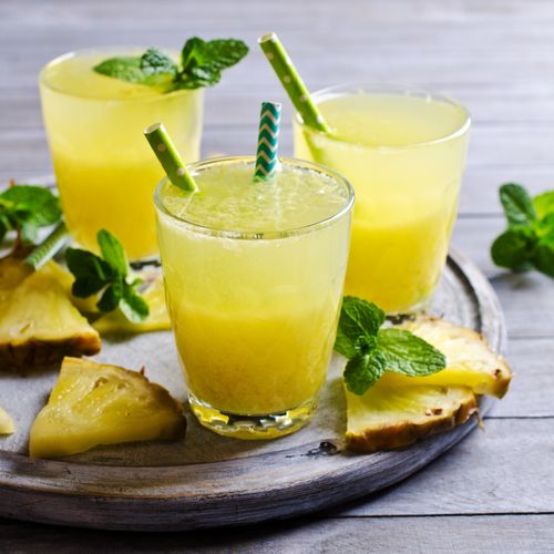Three glasses of pineapple infused drink on a wooden chopping board with mint sprigs - Natural Hydration Drinks