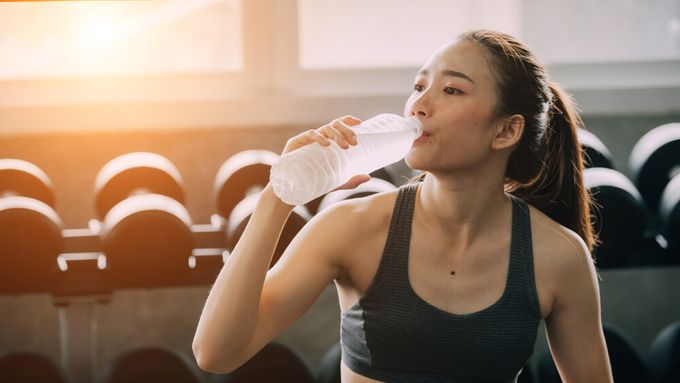 A woman drinking a bottle of cold water in the gym