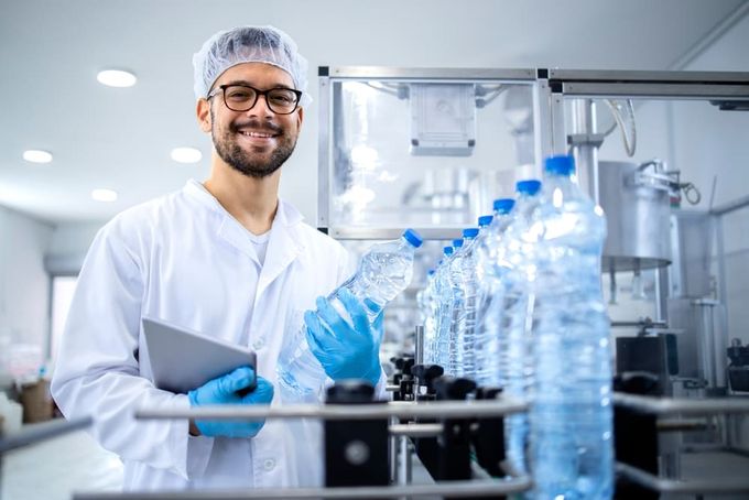 A chemist holding a bottle of packaged water.