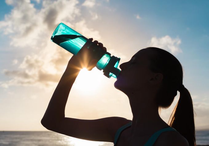 A woman drinking from a bottle fueling up on electrolytes