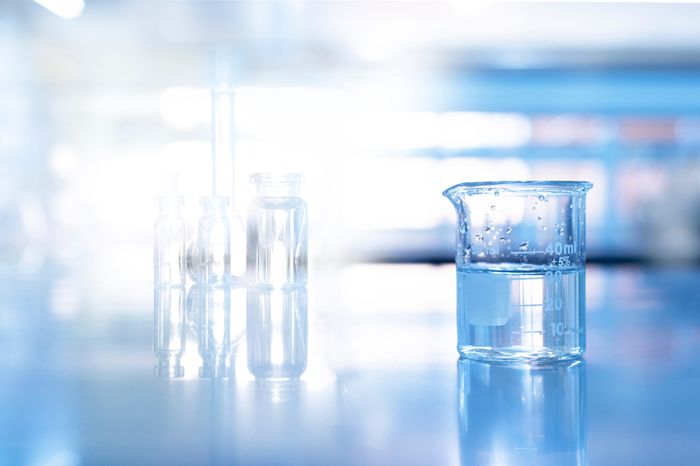Glass beaker in blue science chemistry laboratory background.