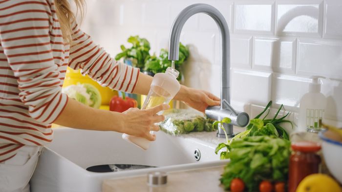 Woman pouring clean, filtered water surrounded by nutrient-rich food