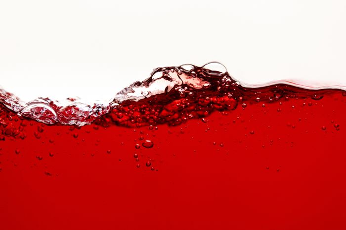 A close up side view image of loose red wine with bubbles