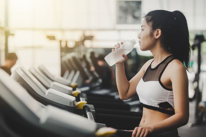 A woman exercising at the gym while drinking a bottle of water