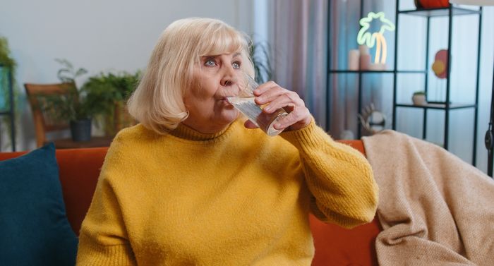 A woman drinking from a glass to rehydrate.
