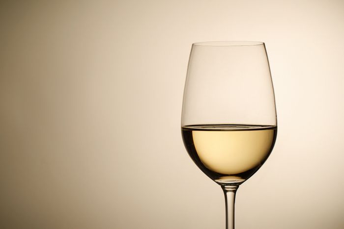 A glass of white wine against a white background