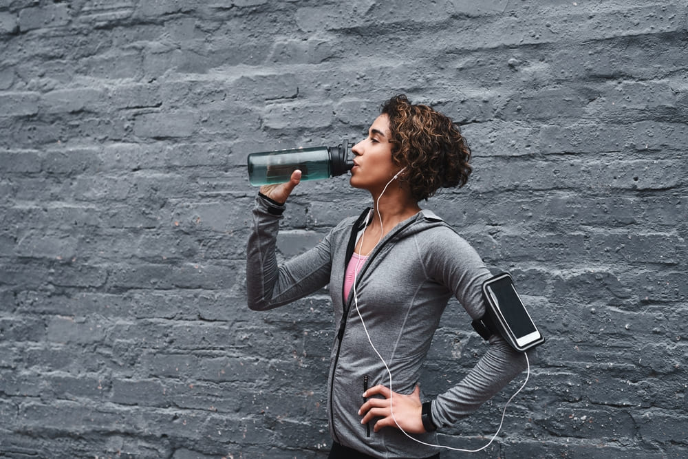 Best way to replace electrolytes after exercise: a woman drinking water.